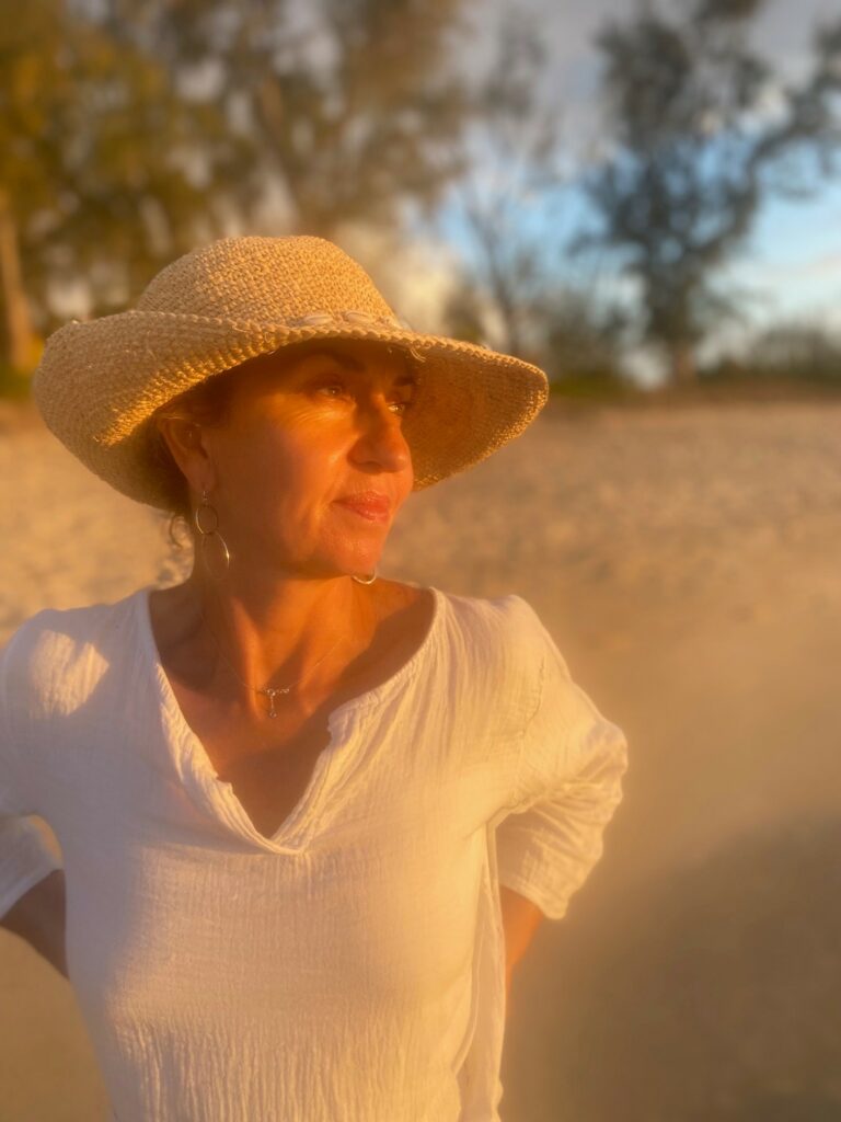 Sylvie Bailly, conseillère en image sur la plage, habillée en blanc, regardant au loin