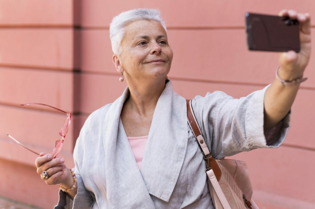 femme senior pimpante aux cheveux courts blanc sur un fond rose