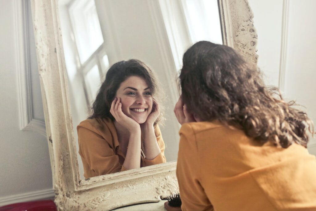 femme souriante qui se regarde dans un miroir avec confiance. Pour la page étapes d'un conseil en image